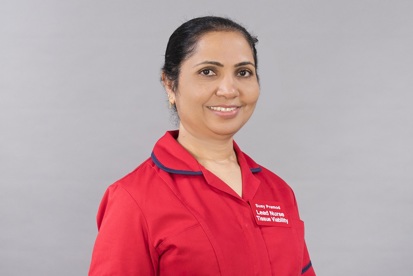 A photo of Susy Pramod, lead nurse in tissue viability at The Christie, wearing a red uniform.
