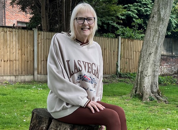 A photo of Christie patient Jan Smith sitting on a tree stump.