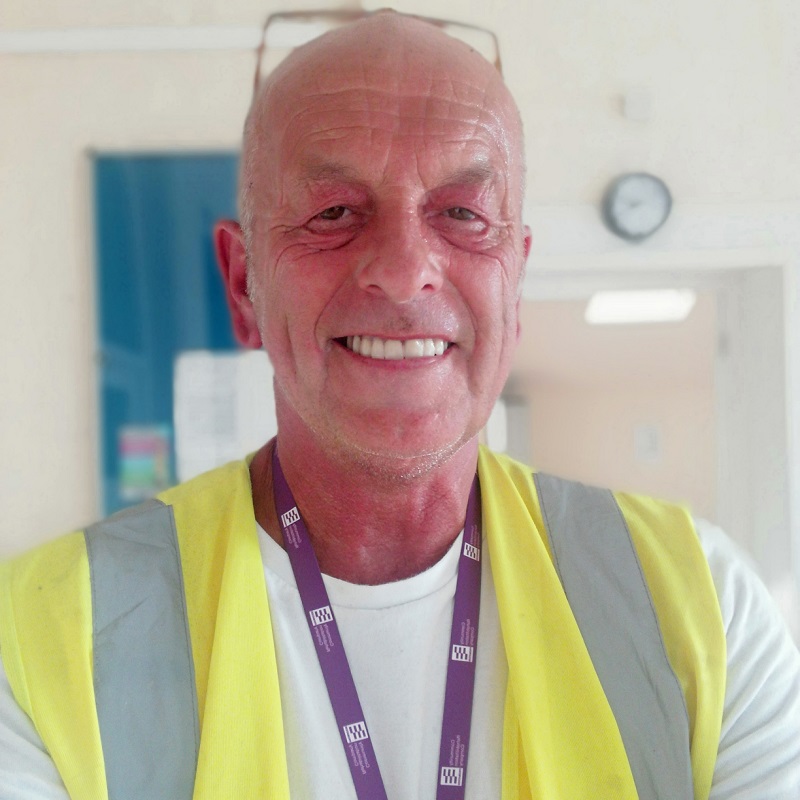 A photo of Christie patient Tony Jackson wearing a high visibility jacket and a lanyard.