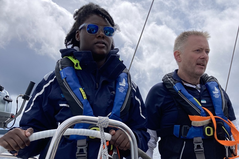 A photo of Christie patient Mercy wearing sunglasses and steering a boat.