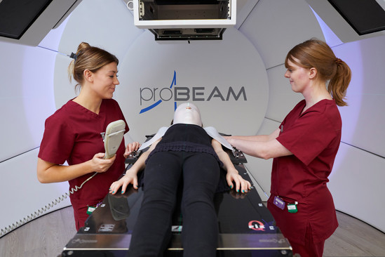 Radiographers with a patient on the robotic couch during proton beam therapy.