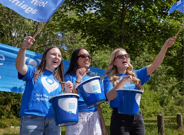 A photo of 3 women wearing Christie Charity t-shirts and holding collection buckets.