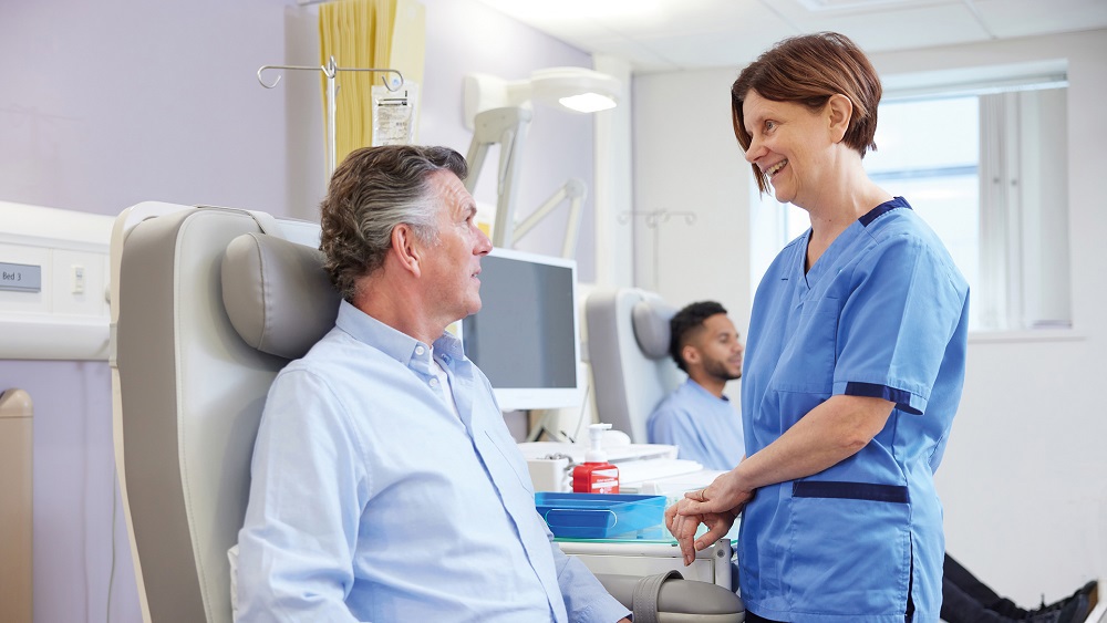 A photo of a female nurse treating a male patient in a chair.