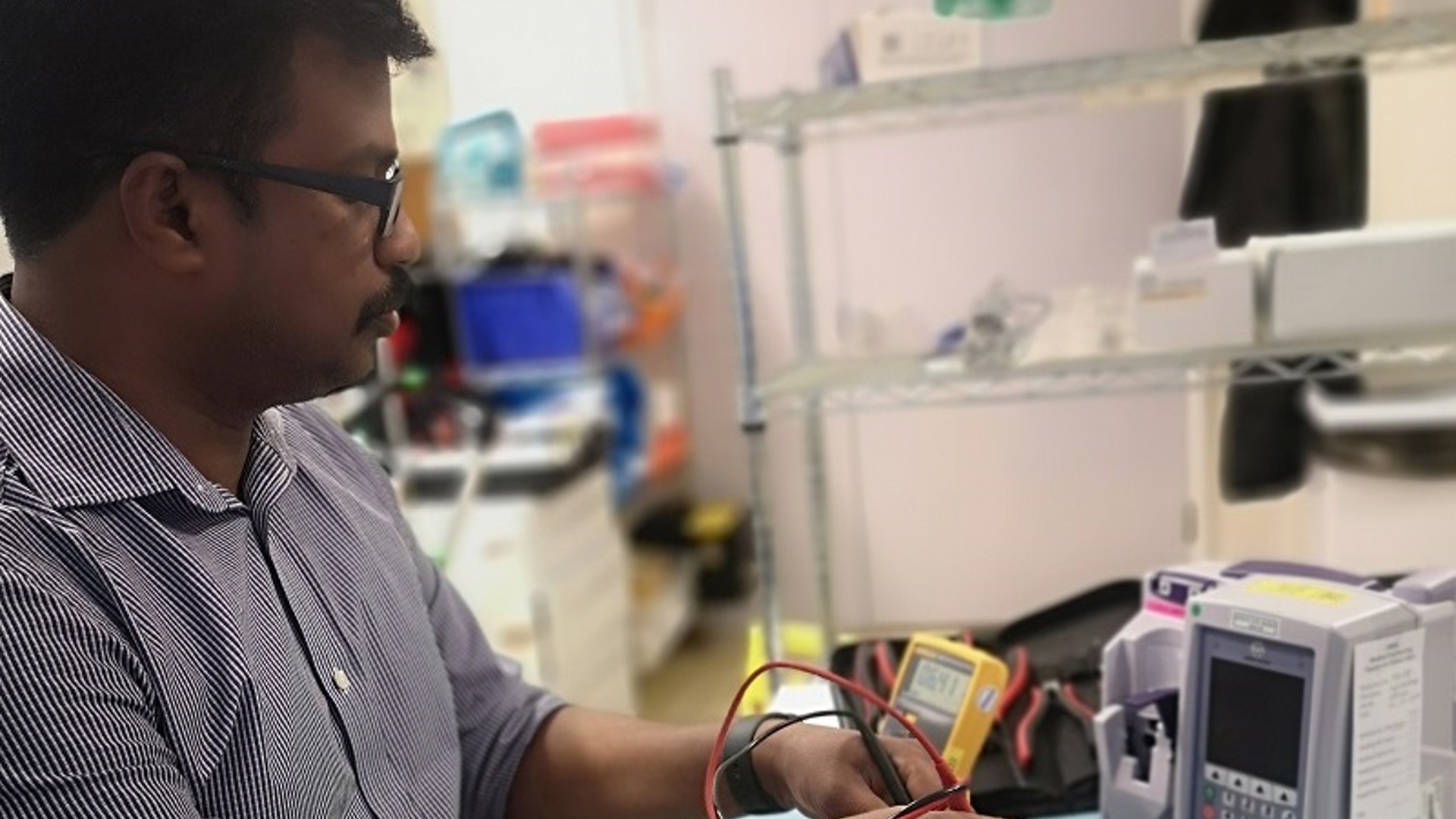 A photo of a man in the clinical engineering department at The Christie connecting some wires to a piece of equipment.