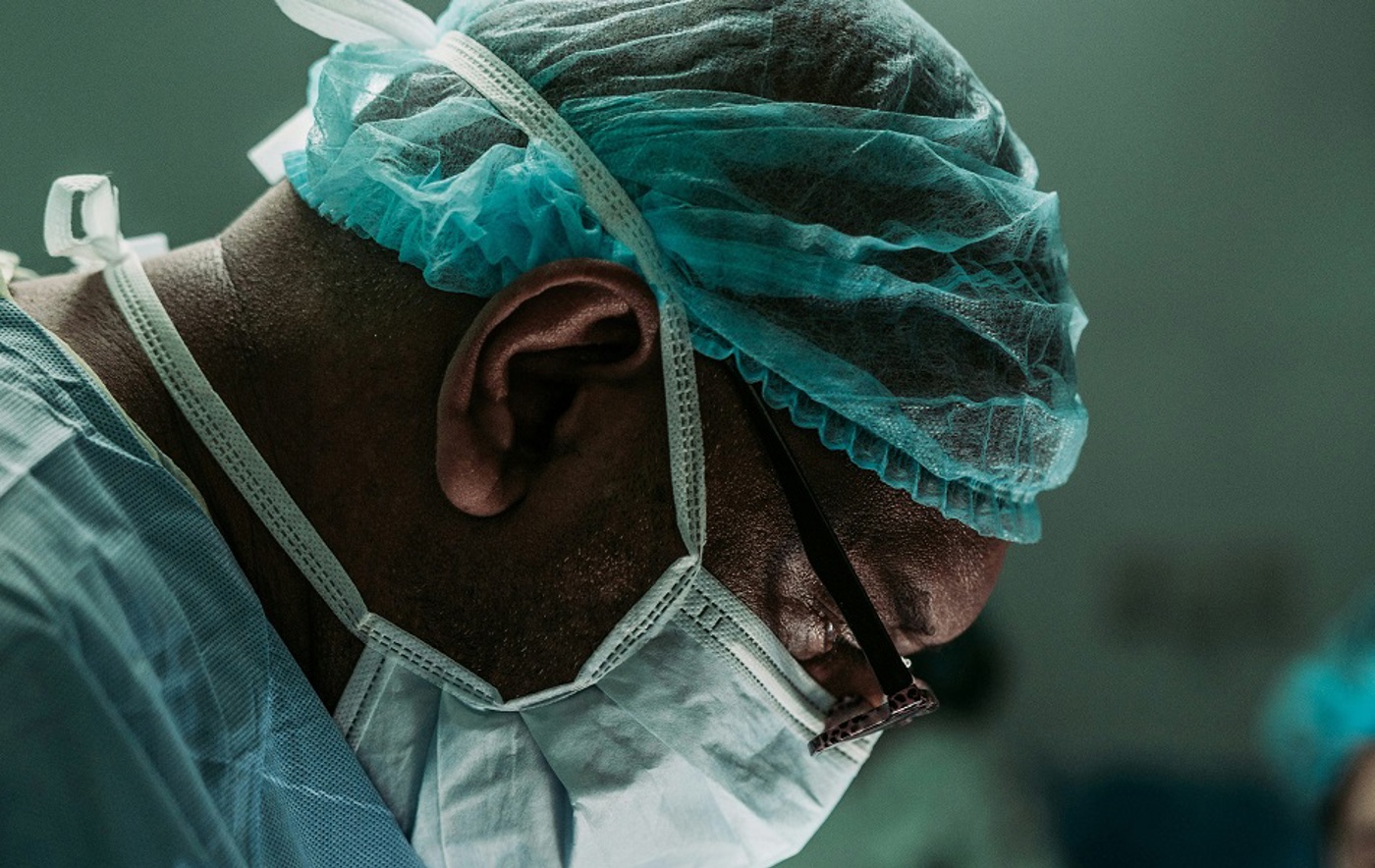 A close-up photo of a surgeon in a surgical mask.