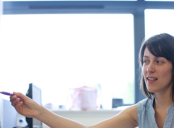 A photo of a woman pointing at a computer screen.