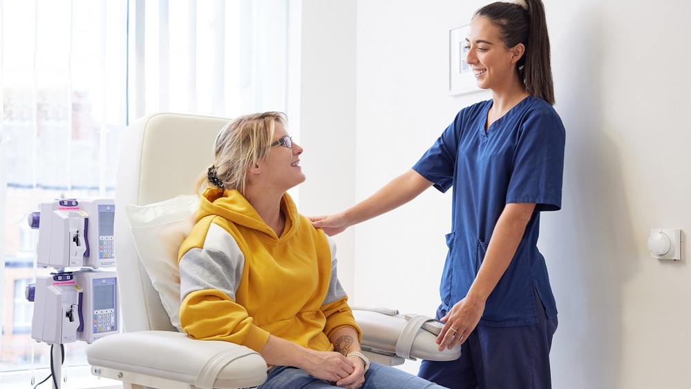 A photo of a nurse looking at a young female patient in a chair.