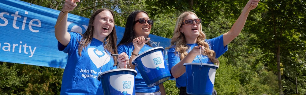 A photo of 3 women wearing Christie Charity t-shirts and holding collection buckets.