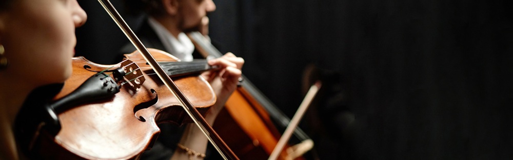 A photo of 2 people playing string instruments; their faces can't be seen.