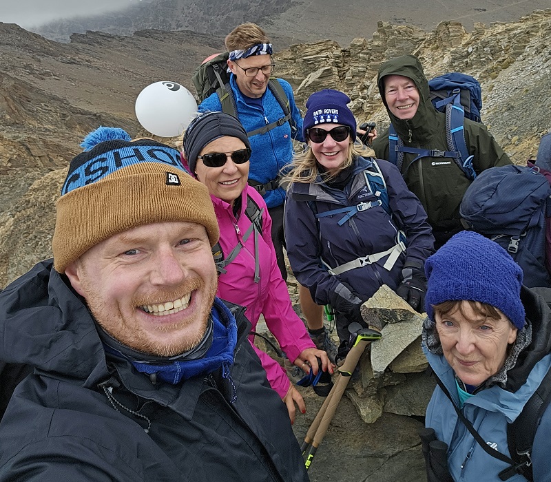 A photo of a group of trekkers on top of a mountain.