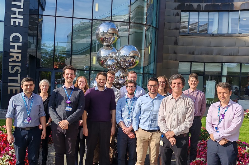 A photo of The Christie Medical Physics and Engineering (CMPE) Magnetic Resonance (MR) Physics group standing outside the Oak Road entrance at The Christie.