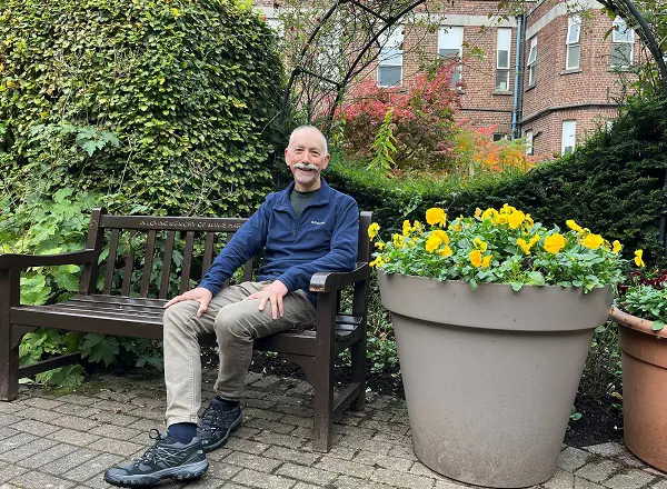A photo of Christie patient Richard Nelson sitting on a bench in The Christie garden.