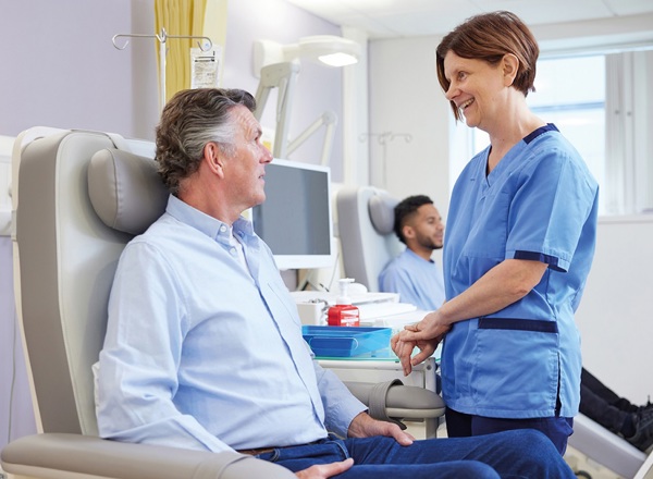 A photo of a female nurse treating a male patient in a chair.
