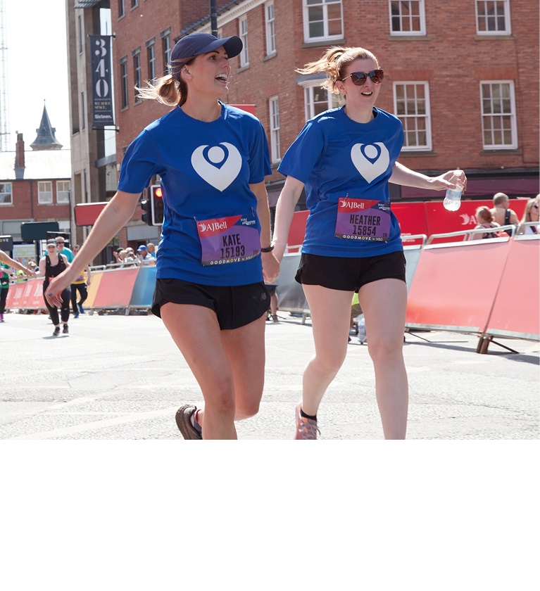 A photo of 2 women in Christie Charity t-shirts running hand-in-hand.
