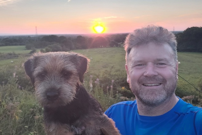 A photo of Christie patient David Maccartney in front of a sunset with his dog Presley.