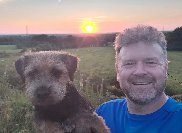 A photo of Christie patient David Maccartney in front of a sunset with his dog Presley.