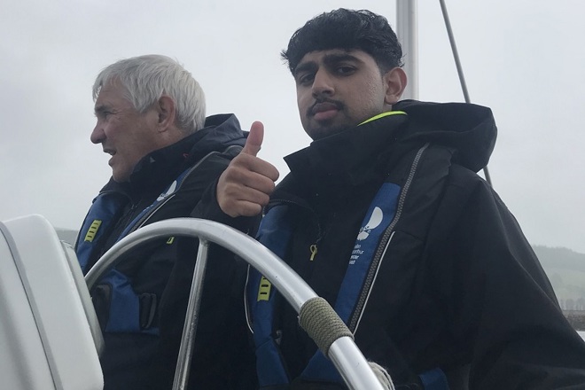 A photo of Christie patient Adil steering a boat.
