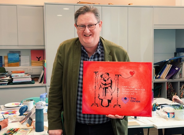A photo of Christie prostate cancer patient, Paul King, posing with painting, Kissing Men.