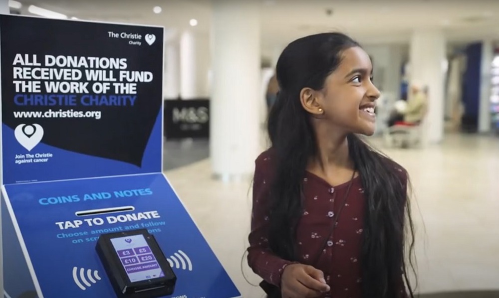 A photo of a girl donating to The Christie Charity using a donation box.