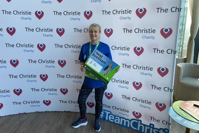 A photo of radiographer Lisa McDaid at The Christie Charity Tower Run, holding a board reading 8:26.