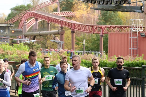 A photo of a group of runners with a rollercoaster in the background.